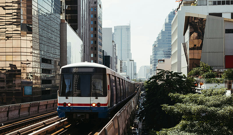 angkok BTS Skytrain traveling on elevated tracks through the city center during the day.