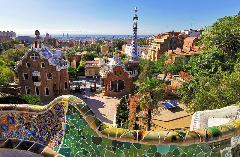 The colorful mosaic terrace and iconic entrance buildings of Park Güell in Barcelona.