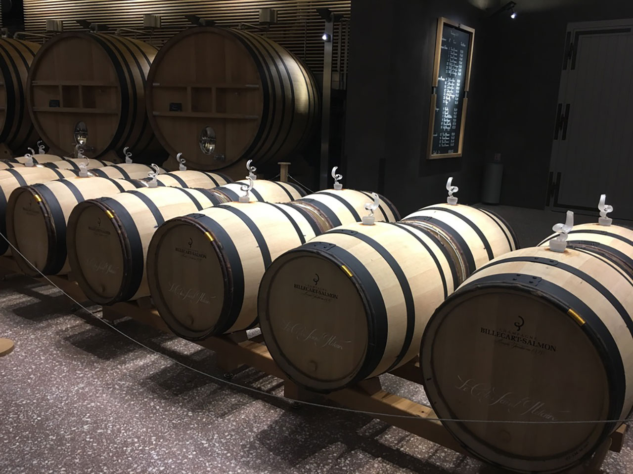 Rows of oak barrels aging wine in the dimly lit cellars of the Billecart-Salmon champagne house
