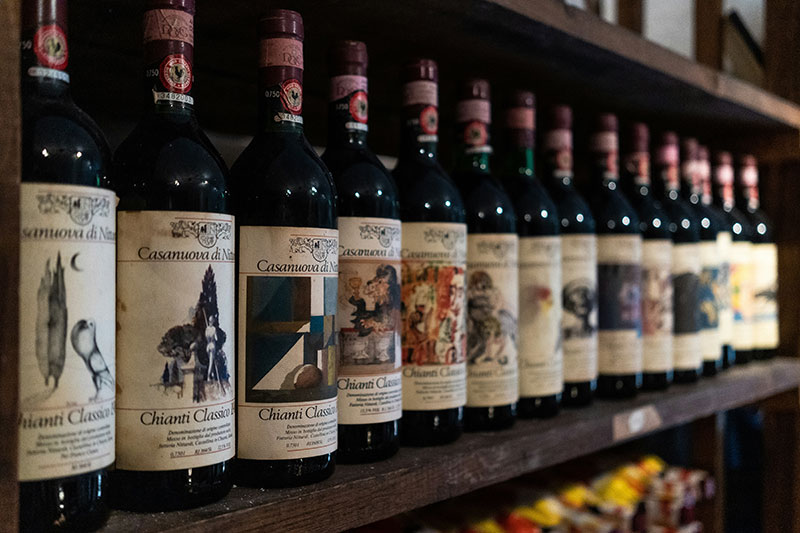 Row of Chianti Classico wine bottles at Nittardi winery in Tuscany featuring the Gallo Nero black rooster seal.