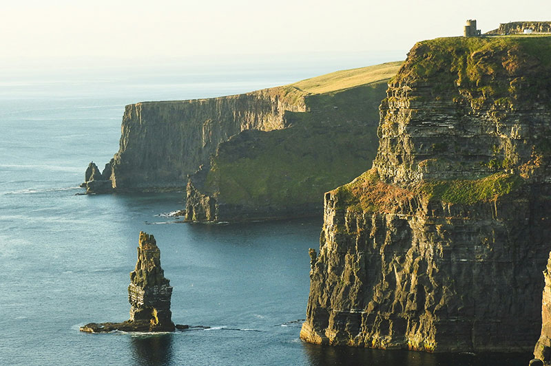 The iconic Cliffs of Moher in Ireland, towering over the Atlantic Ocean with a sea stack visible.