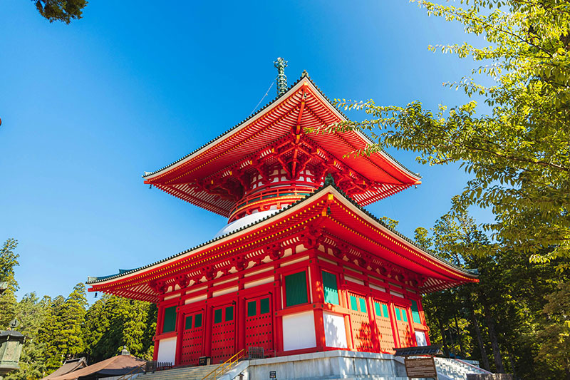 Here are options for the ALT tag and caption for the image of the Kompon Daito in Koyasan. ALT Tag (Accessibility & SEO) Recommended: The vermilion-colored Kompon Daito (Grand Central Pagoda) at the Danjo Garan complex in Koyasan, Japan, showcasing traditional two-story tahoto architecture surrounded by greenery.