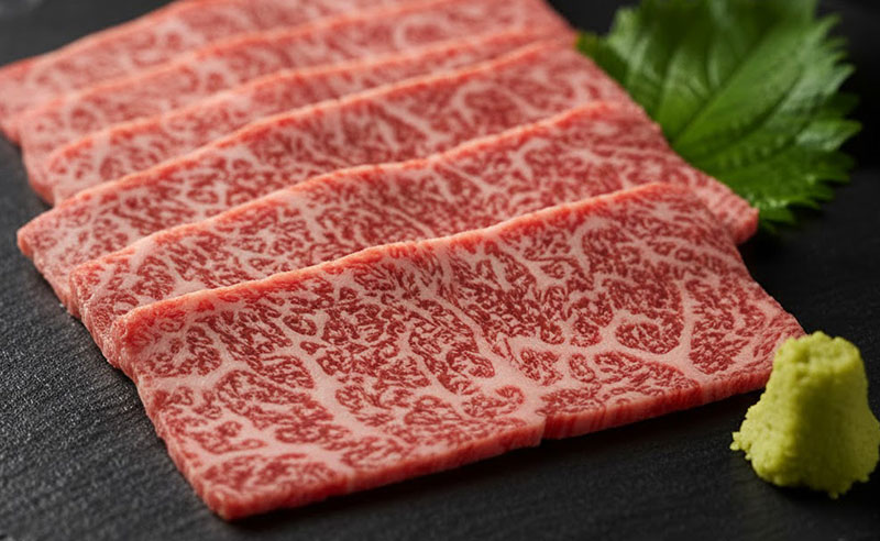 A close-up photo of raw A5 Japanese Wagyu beef slices on a plate, showcasing its intense marbling and rich texture.
