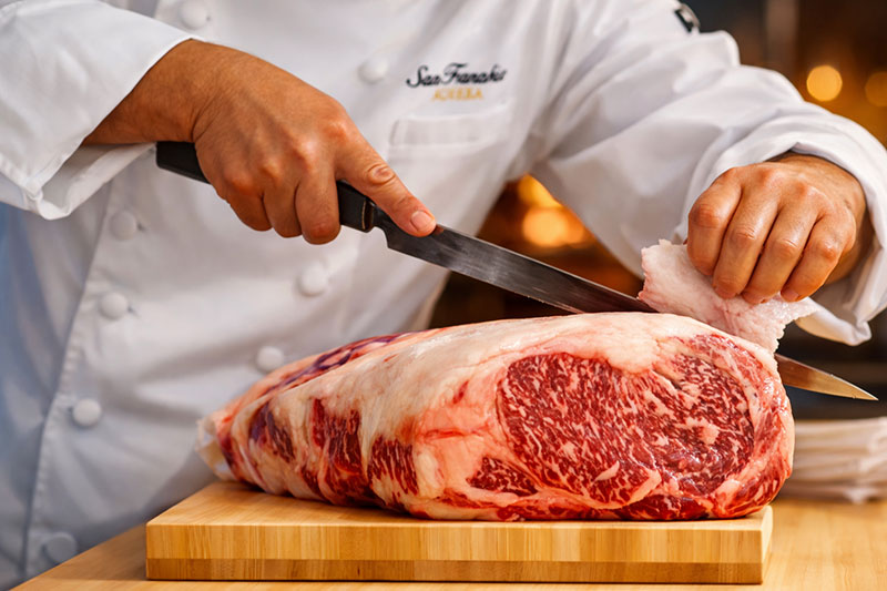 Chef trimming a highly marbled A5 Wagyu beef cut on a wooden board in a Tokyo restaurant