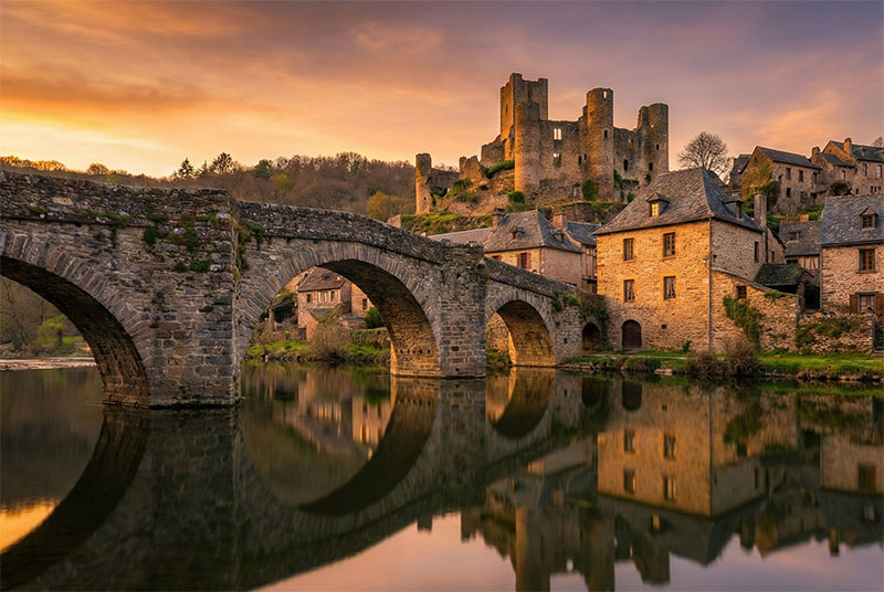 The medieval stone bridge and castle of Belcastel reflecting in the river in Aveyron.