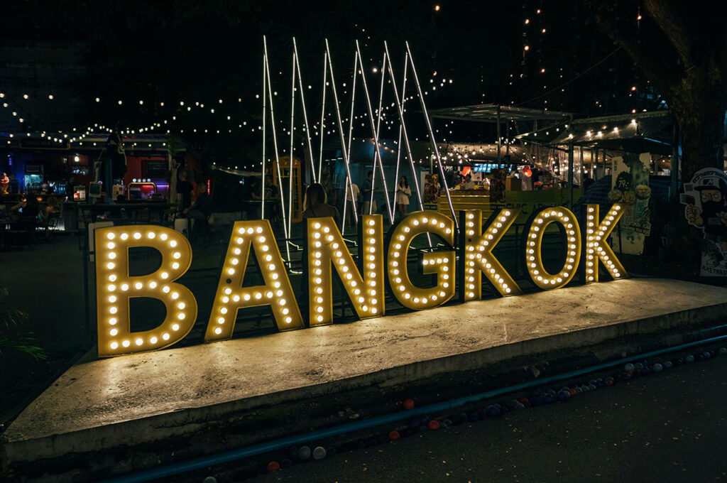 Large illuminated "BANGKOK" neon sign glowing against a dark night sky.