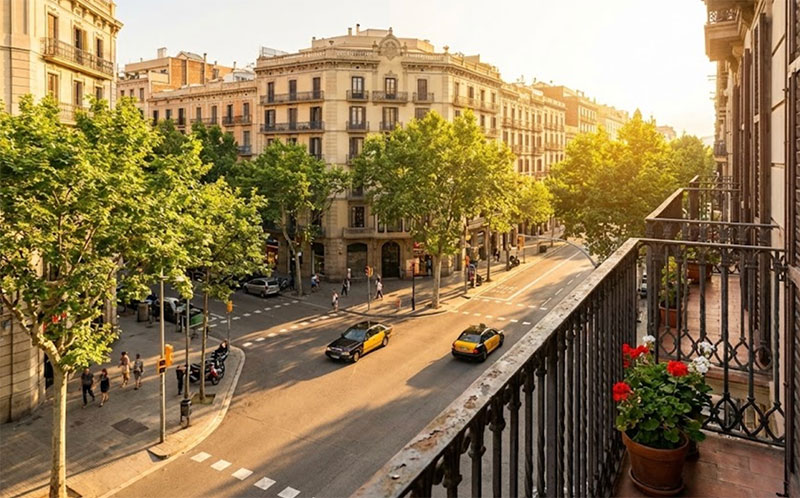 Sunlit interior of a boutique hotel room in Barcelona with tiled floors and open French doors leading to a balcony.