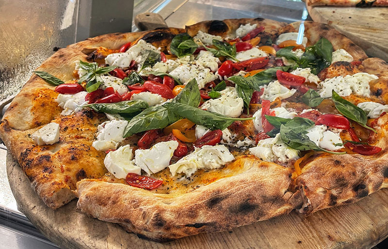 The "Local Eats" 10: Essential Tastes of Italy As a Local Guide, I believe you haven't truly visited Italy until you've tasted it. Since you are traveling through the "Holy Trinity" of Rome, Florence, and Venice, here are the essential foods and drinks that define this route. Consider this your edible checklist. Local Guide Tip: Coperto & Servizio Don't be alarmed if you see a "Coperto" charge (usually €2–3 per person) on your bill; it is the standard cover charge for sitting down. Tipping is not mandatory like in the US, so rounding up the bill is sufficient. Morning Rituals & Sweet Breaks The Coffee Culture (Cappuccino vs. Espresso): There is a strict rule here: Cappuccino is for breakfast (no milk after 11:00 AM!). Espresso (un caffè) is the all-day energy boost. Drink them standing at the bar for the true local experience (and price). Cornetto al Cioccolato: Often mistaken for a French croissant, the Italian cornetto is slightly denser, sweeter, and made with eggs. A warm cornetto filled with chocolate cream (or pistachio) is the only way to start a Roman morning. Gelato Artigianale: You will likely eat this every day. Look for "Artigianale" (homemade) and avoid the shops with big, fluffy mounds of bright colors (that’s fake!). Real pistachio gelato should be a dull, earthy green, not neon. The Roman Lunch & Dinner Pizza Margherita (Wood-Fired): You are looking for the "DOC" designation. Simple, fresh tomato sauce, mozzarella di bufala, and basil. In Rome, look for the thinner, crispy crust; if you spot a Neapolitan place, expect the soft, pillowy crust. Both are non-negotiable must-haves. Cacio e Pepe: The most famous of the four Roman pastas. It translates literally to "Cheese and Pepper." It sounds simple, but creating a creamy sauce using only Pecorino Romano cheese, pasta water, and toasted black pepper is an art form. The Tuscan Savory Gap Prosciutto di Parma: While in Florence, order a "Tagliere" (meat and cheese board). The Prosciutto di Parma should be sliced paper-thin so it practically melts on your tongue. It’s sweet, salty, and perfect. Parmigiano Reggiano: Forget the shaker cheese you know from home. Real "Parmesan" is aged (12, 24, or 36 months) and served in jagged chunks. It is often served with a drop of balsamic vinegar or honey as an appetizer. Local Guide Tip: The Perfect Tuscan Pairing There is truly nothing better than a beautiful plate of antipasto consisting of salty Prosciutto, Salami, and chunks of Parmigiano Reggiano matched with a glass of Chianti Classico. The fats in the cured meats cut through the tannins of the red wine perfectly. It is the ultimate Tuscan lunch. Thirsty for more Tuscany? The world of Tuscan wine goes far beyond Chianti in a straw basket. From "Super Tuscans" to Brunello, learn what to order so you don't look like a tourist at the wine bar. Read More: The Tuscan Wine Guide & Super Tuscans The Venetian Finish Seafood Pasta (Spaghetti alle Vongole): When you hit the coast or Venice, switch immediately from meat to seafood. Spaghetti with clams (vongole), white wine, garlic, and parsley is the quintessential dish of the lagoon. Aperol Spritz: This iconic orange drink was born in the Veneto region (near Venice). It is the golden hour standard: Prosecco, Aperol, and soda water. Enjoy it at sunset near the Rialto Bridge. Limoncello: The grand finale. This is a digestivo, a high-alcohol lemon liqueur served ice-cold in a chilled shot glass after a heavy dinner to help you digest. It’s "sips," not "shots"!