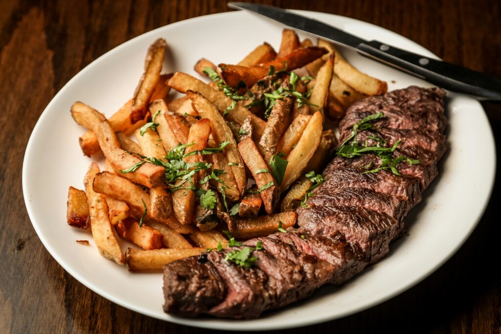 Classic French steak frites served with herb butter and a side of golden french fries.