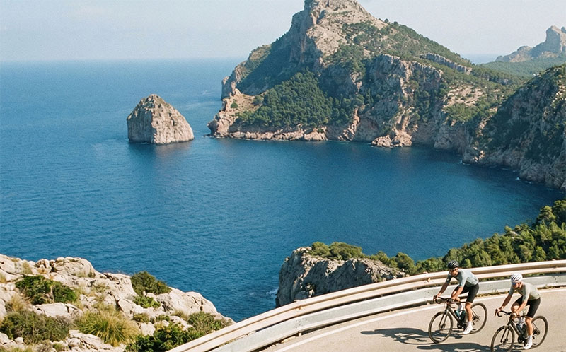 Overhead view of a group of cyclists riding a winding mountain road along the coast of Mallorca, Spain