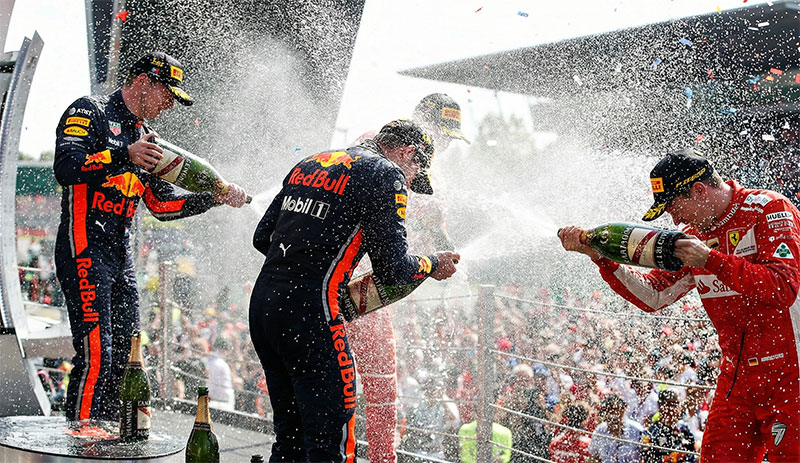 Formula 1 race winners celebrating on the podium by spraying a Magnum bottle of champagne, a tradition that began in 1967.