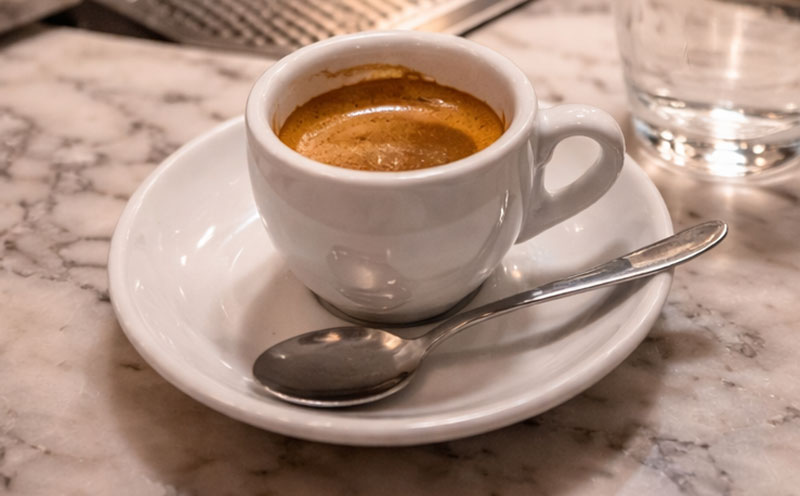 A single espresso cup served at the standing counter of an Italian coffee bar.