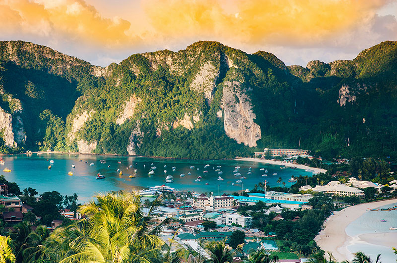 A panoramic sunset view of the twin bays of Koh Phi Phi Don from the famous viewpoint, showing the limestone cliffs and turquoise water that make it a key stop on Thailand island itineraries