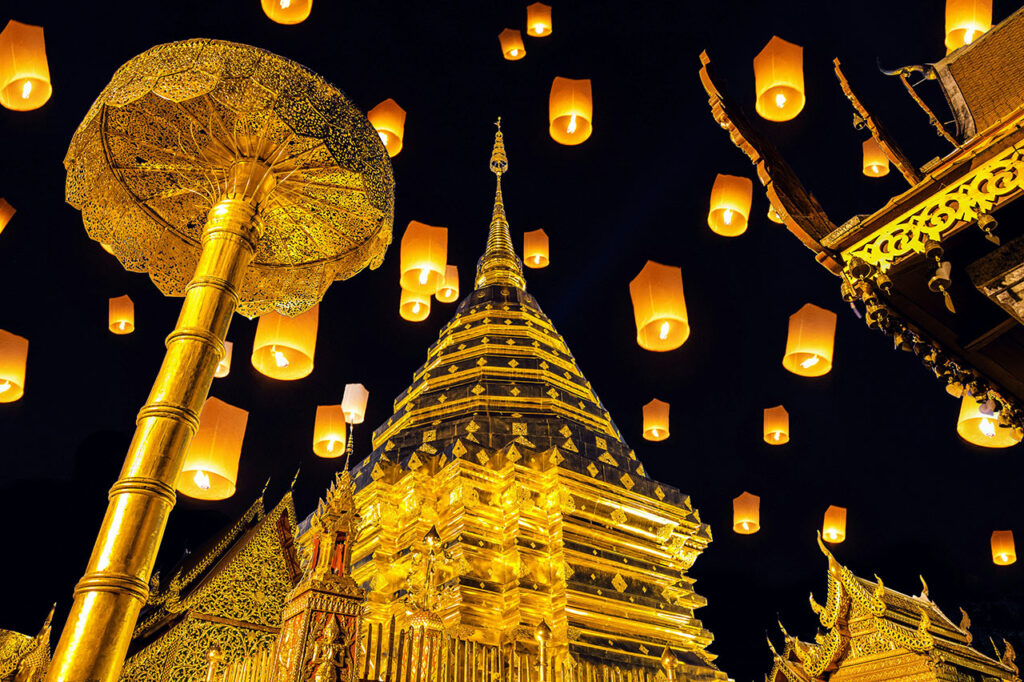 Thousands of glowing paper lanterns floating into the night sky during the Yi Peng festival in Chiang Mai.