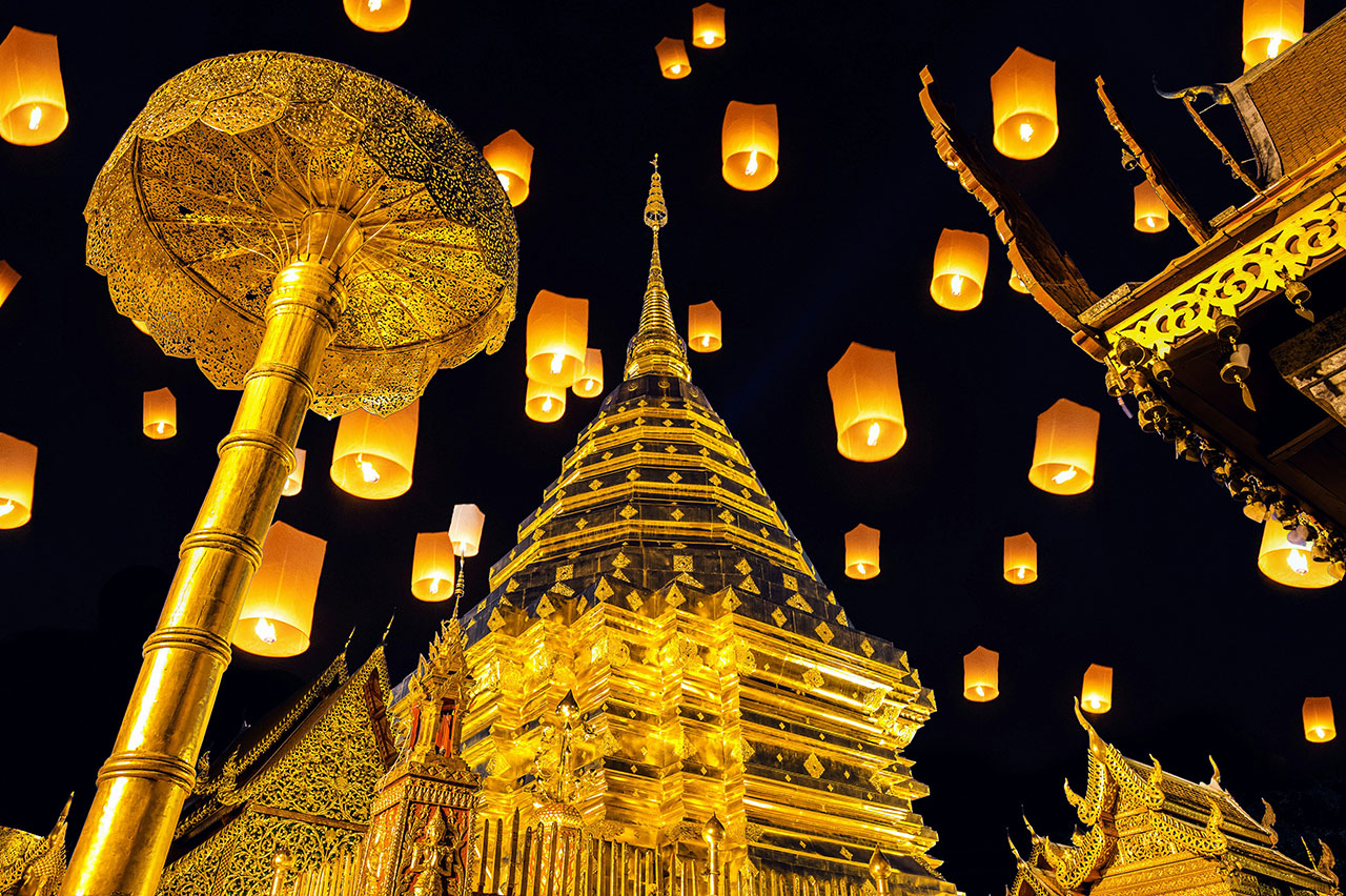Thousands of glowing paper lanterns floating into the night sky during the Yi Peng festival in Chiang Mai.