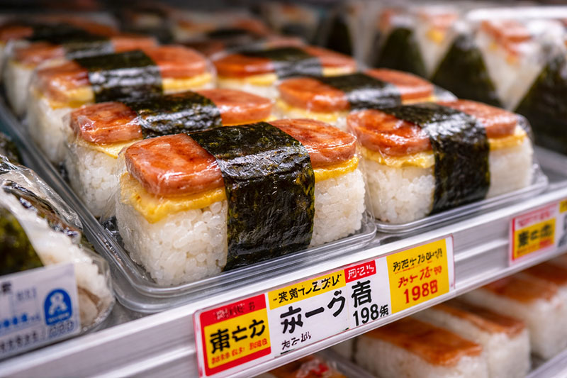 Close-up of SPAM musubi wrapped in nori and stacked in a convenience store display case in Okinawa, Japan.