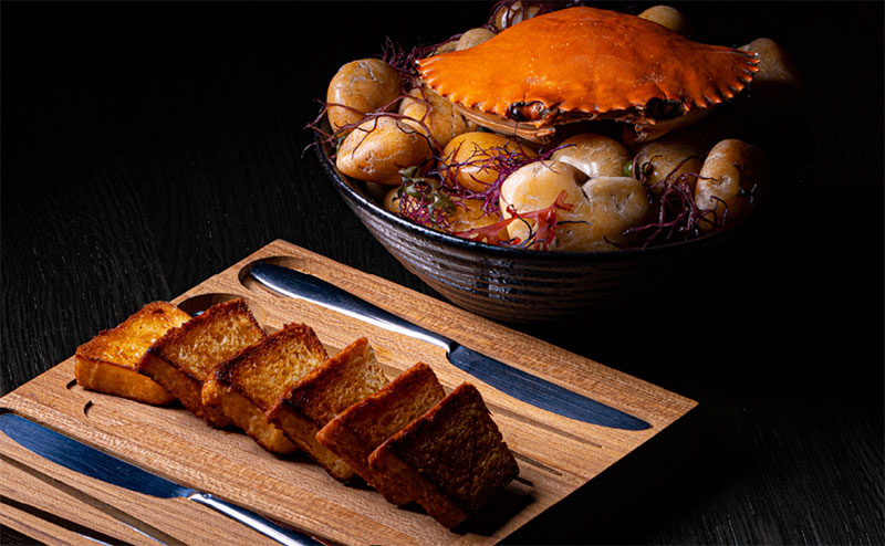 Crab toast course with toasted brioche and crab preparation at POTONG Michelin-star restaurant in Bangkok.