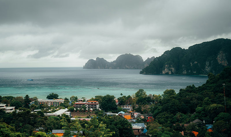 Panoramic view of Koh Phi Phi Don's twin bays under a cloudy grey sky during the rainy season.