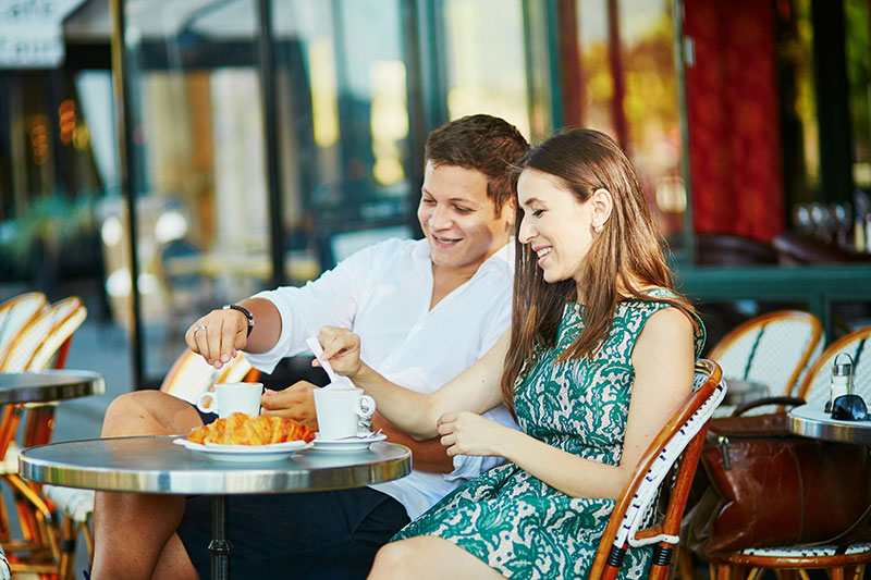 A couple relaxing at an outdoor French cafe table, illustrating the tourist experience in France.