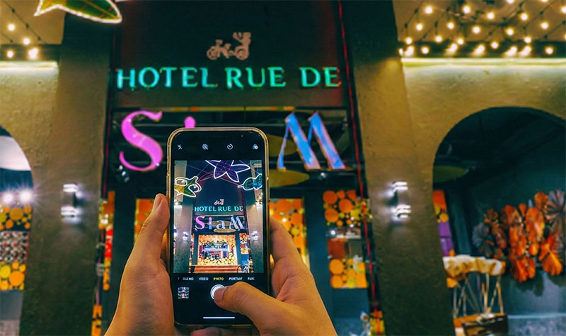 Person taking a picture of their hotel sign to save the address on their phone.