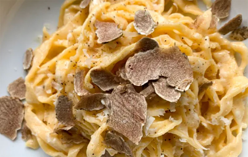 A close-up of fresh egg pasta covered in generous shavings of white truffle at a restaurant in Rome.