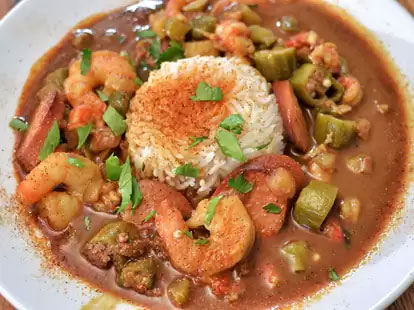 A close-up of a traditional Creole dish from Dooky Chase’s Restaurant, featuring a hearty serving of gumbo with rice, shrimp, and okra in a rich, dark roux.