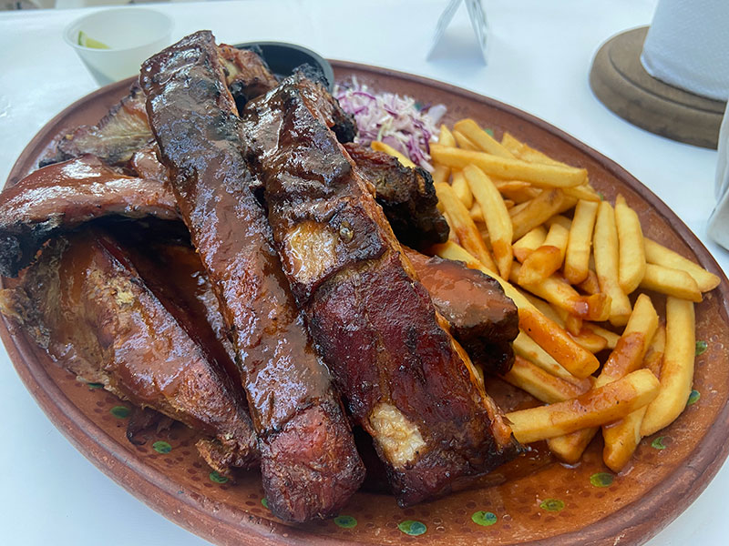 Close-up of BBQ ribs and french fries on a plate at La Huerta BBQ & Grill.