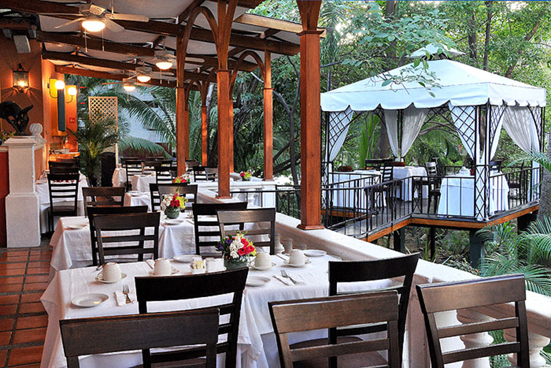 Dining tables set on the open-air patio of River Café, overlooking the Cuale River in Zona Romántica.