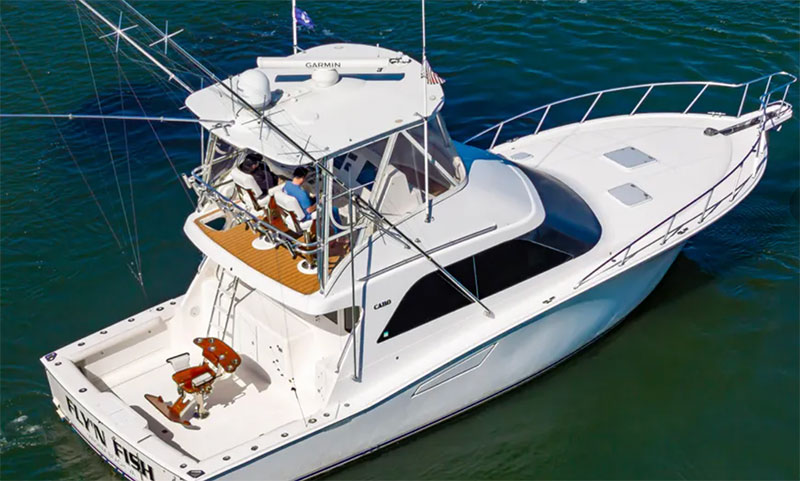 A white sport fishing boat cruising through the deep blue waters of Cabo San Lucas, equipped with fishing rods and outriggers for deep-sea angling.