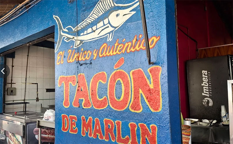 Brightly painted 'Tacon de Marlin' sign on the exterior wall of the restaurant.
