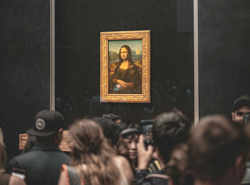 Leonardo da Vinci's Mona Lisa painting on display behind glass at the Louvre Museum.