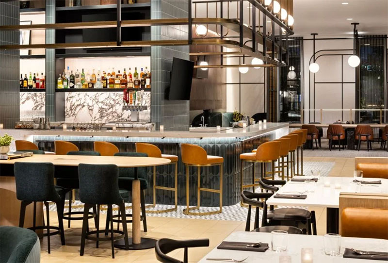 An interior view of Esther's Kitchen in the Las Vegas Arts District, featuring a long, modern bar with seating, warm lighting, and an industrial-chic aesthetic.