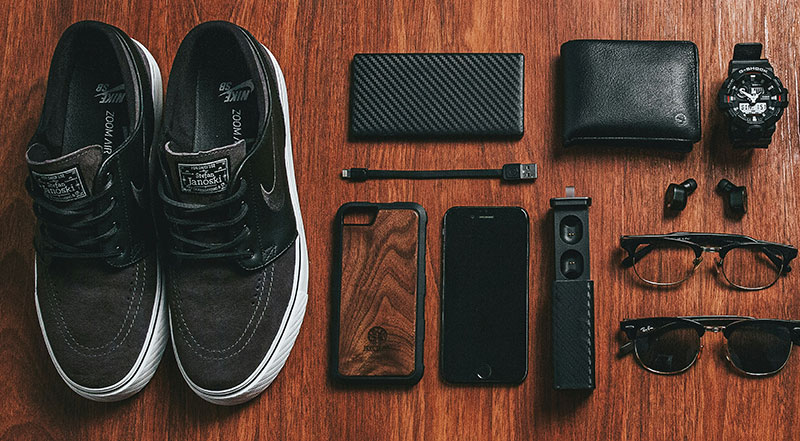 A flat lay of minimalist, black travel gear and accessories organized neatly in preparation for a trip.