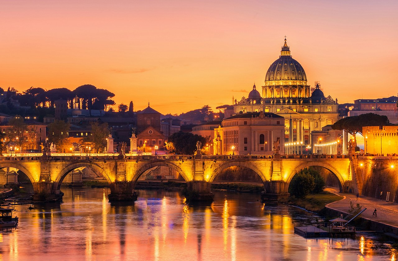 A horizontal, eye-level shot captures the Ponte Sant'Angelo bridge in Rome during the golden hour. The bridge, with its ancient stone arches and white marble angel statues, stretches across the Tiber River