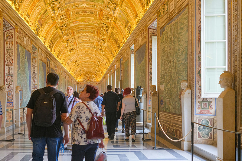 A long, symmetrical interior shot looking down the ornate Gallery of Maps within the Vatican Museums.