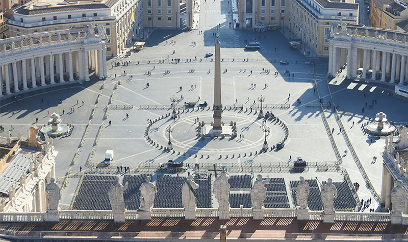 A high-angle, wide-reaching shot looks down onto the vast, elliptical St. Peter's Square from the roof of the basilica