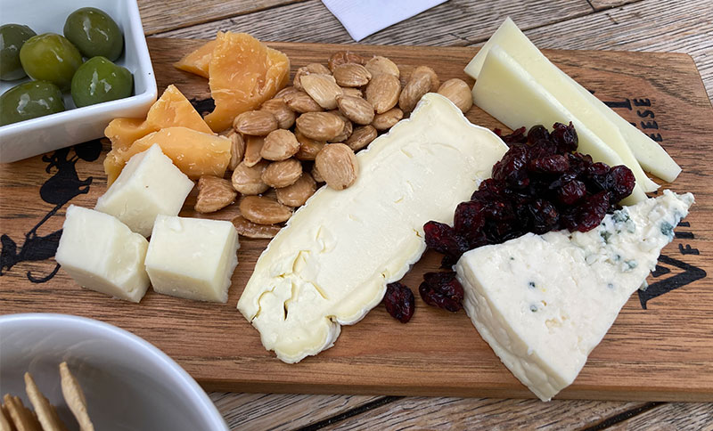 A close-up of a cheese and charcuterie board from Vivant Fine Cheese in Paso Robles, featuring various cheeses, nuts, and dried fruits.