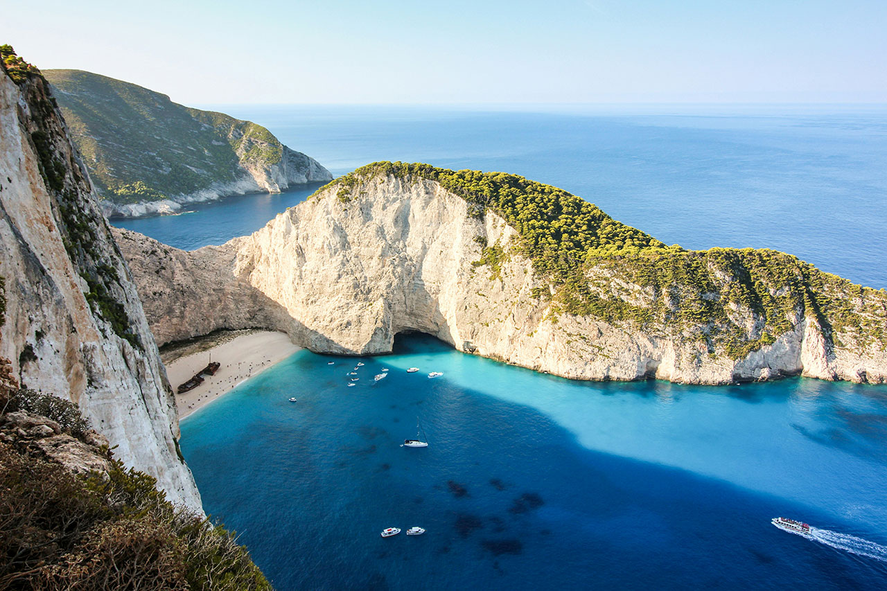 A high-angle view of Navagio Beach, also known as Shipwreck Beach, on the coast of Zakynthos, Greece, with turquoise waters and white cliffs.