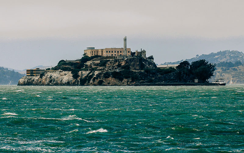 A view of the historic Alcatraz Island prison facility surrounded by the turbulent waters of the San Francisco Bay