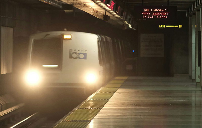 A BART train arriving at a dimly lit underground transit station in San Francisco