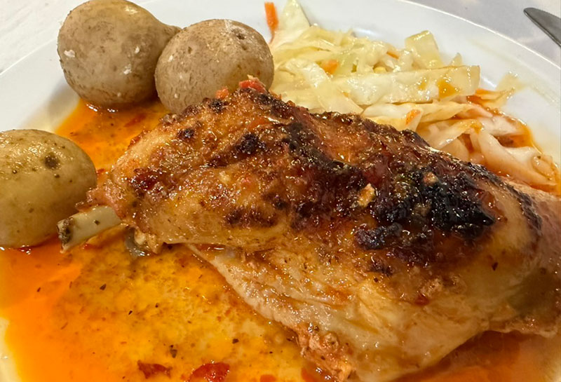 Traditional Camino de Santiago Menu del Peregrino dinner with caldo gallego soup, roast chicken with potatoes, bread, flan dessert, and red wine on a rustic table in a Spanish albergue
