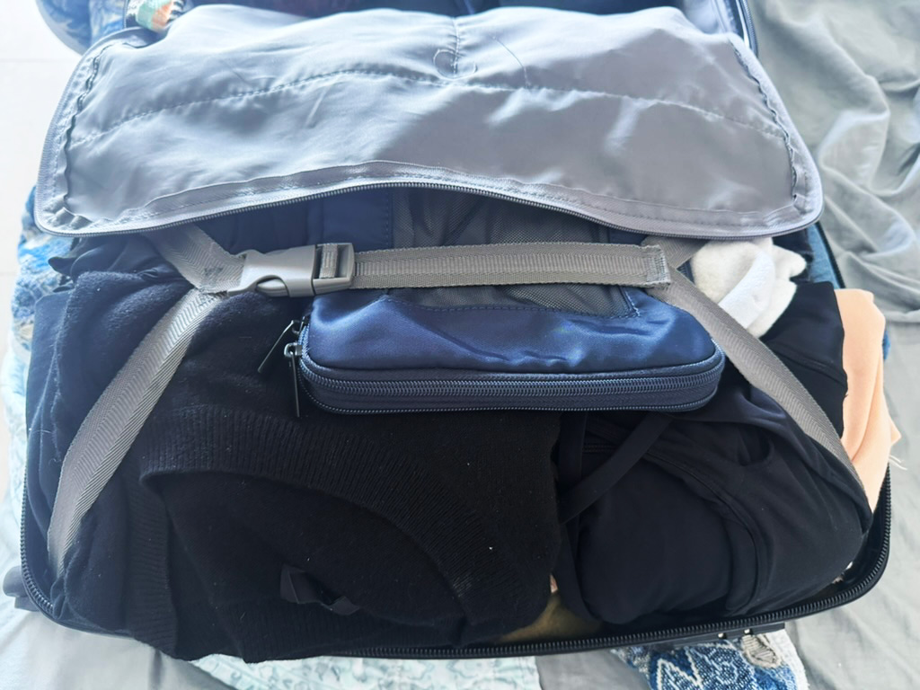Carry-on suitcase packed for travel with clothing and essentials in a real-world packing setup