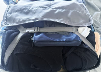 Carry-on suitcase packed for travel with clothing and essentials in a real-world packing setup laid out on a bed