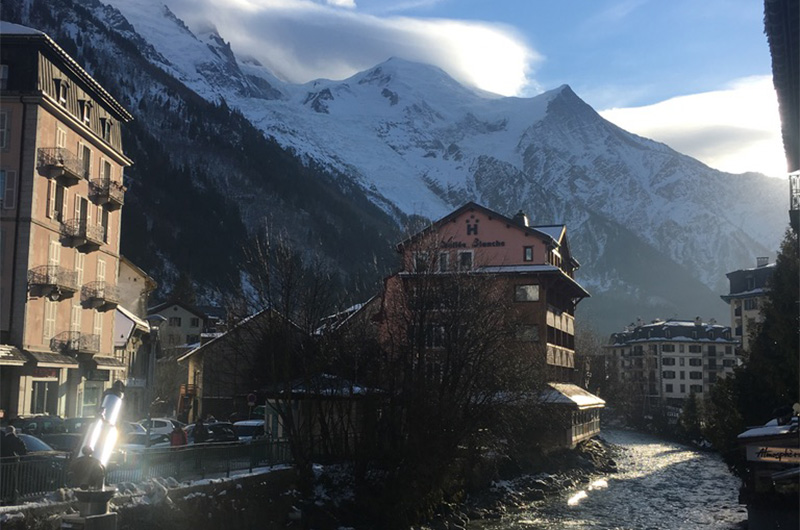 The Arve River flowing through the town of Chamonix with traditional alpine buildings and Mont Blanc in the background.