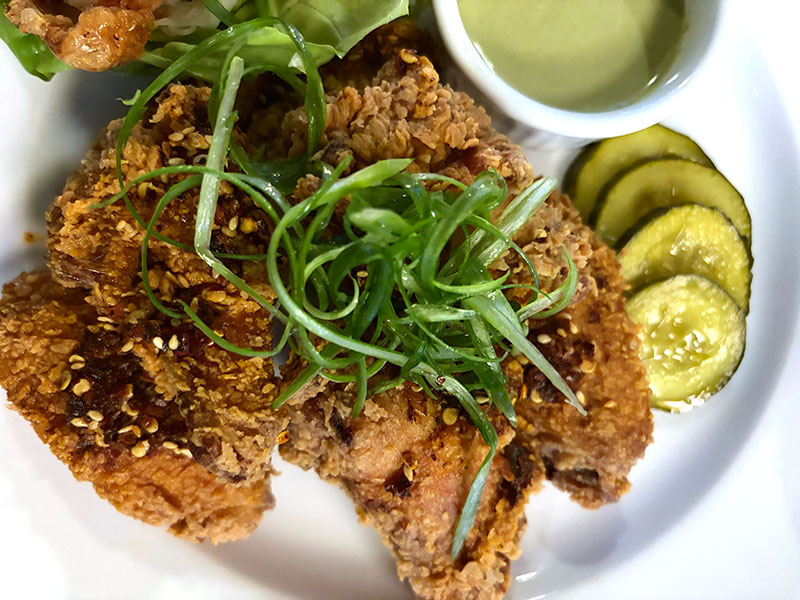 Crispy fried chicken wings topped with chili crunch and scallions, served with green garlic ranch and house pickles.