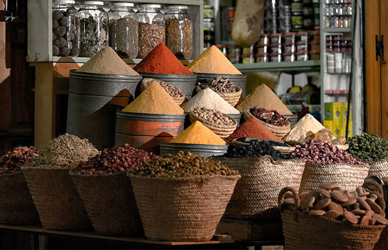 Large mounds of vibrant spices in baskets at a traditional Moroccan souk.