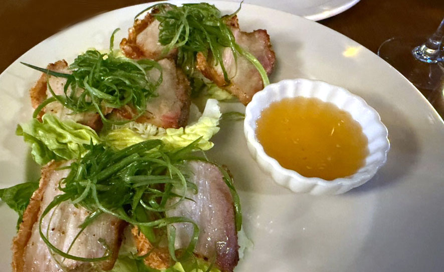 Slices of crispy pork belly served on butter lettuce with a side of fish sauce vinaigrette.