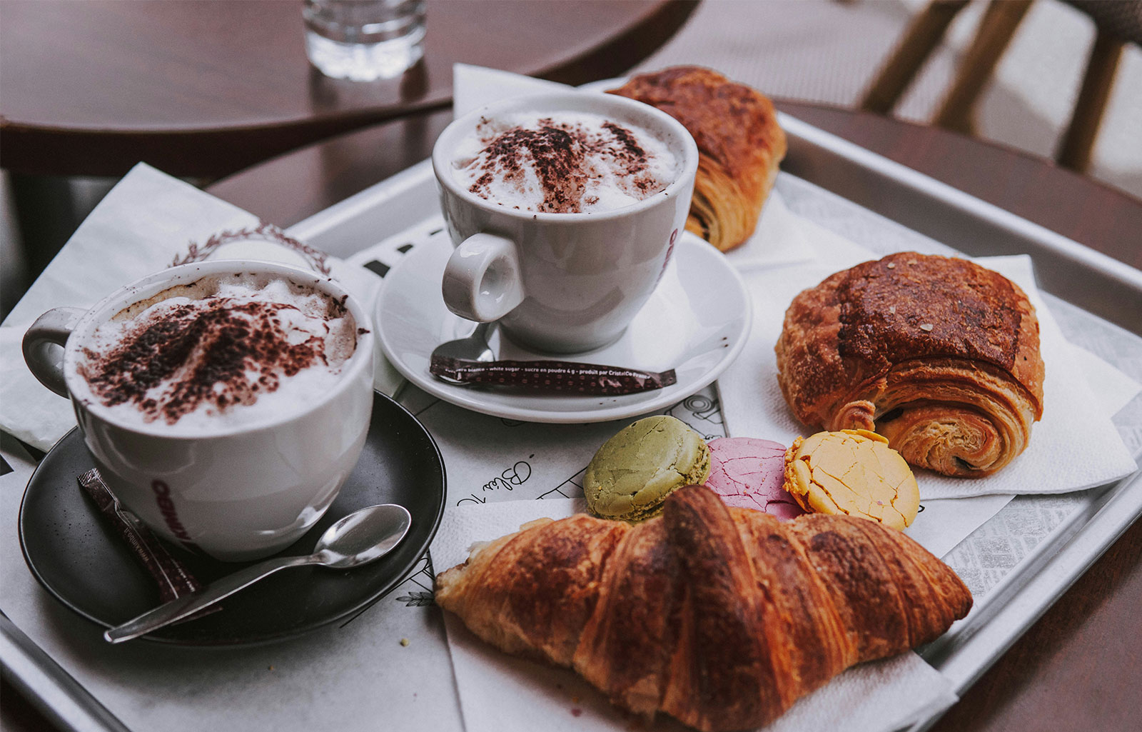 A cozy Parisian breakfast scene with a steaming bowl of cafe au lait, a flaky golden croissant, and a pain au chocolat on a rustic wooden table.