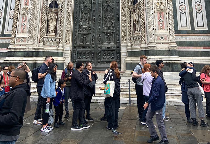 Travelers standing in front of the cathedral doors at Piazza del Duomo in Florence