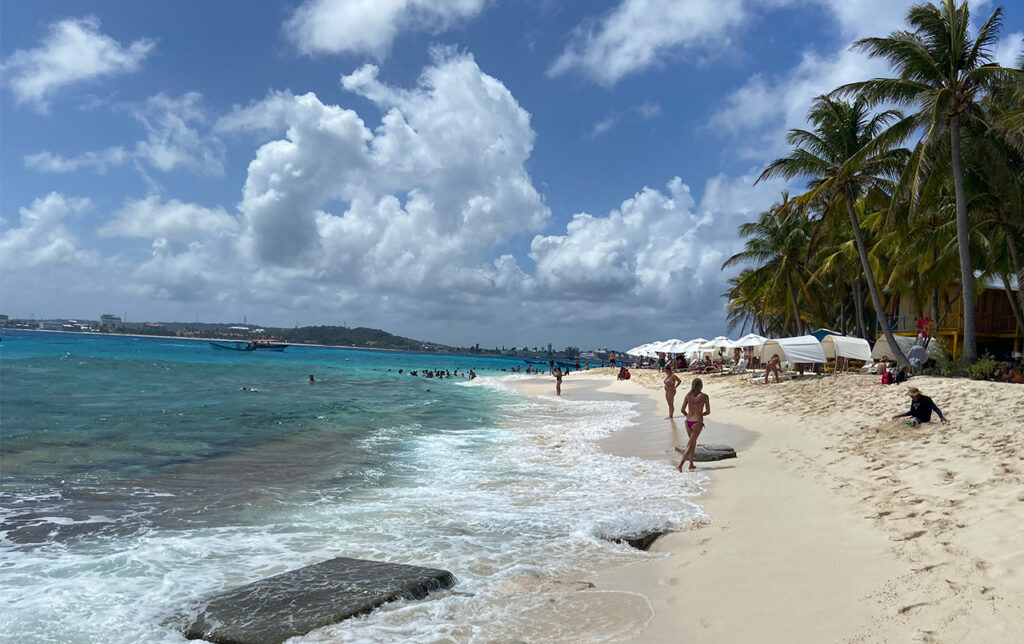 Johnny Cay beach with people walking and white umbrellas.